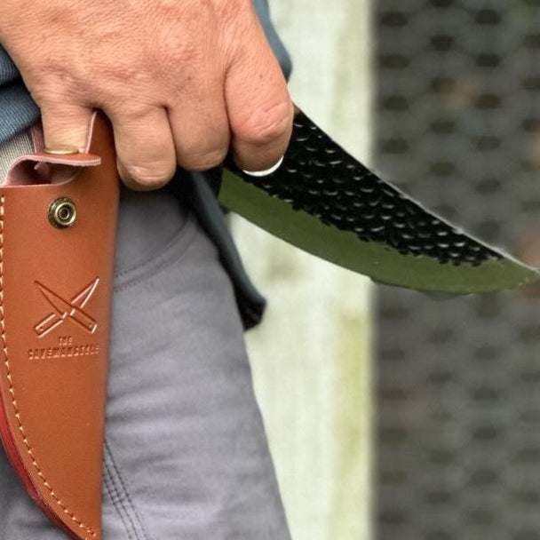 holding a  Caveman knife with a leather sheath, 